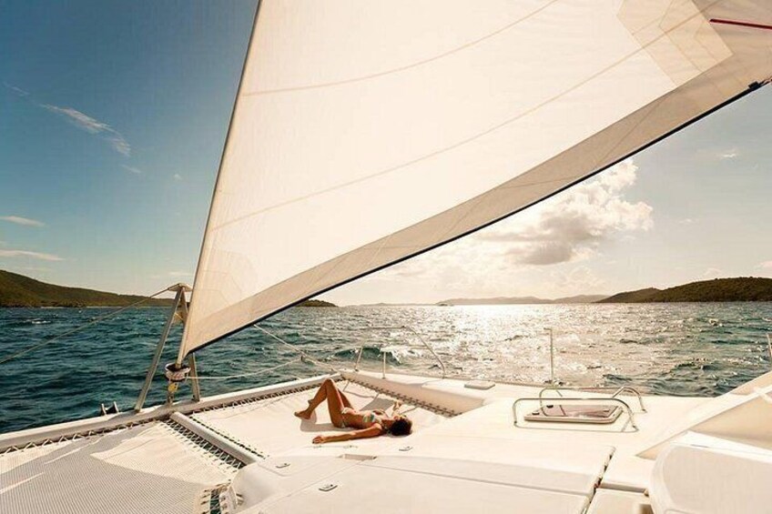 Eine Segelyacht mit einer Person auf dem Deck, ruhiges Meer und Land in der Ferne. 5