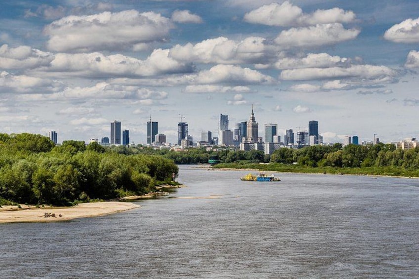 A river with a city skyline in the background, a boat on the water, and dense greenery along the riverbank. 3