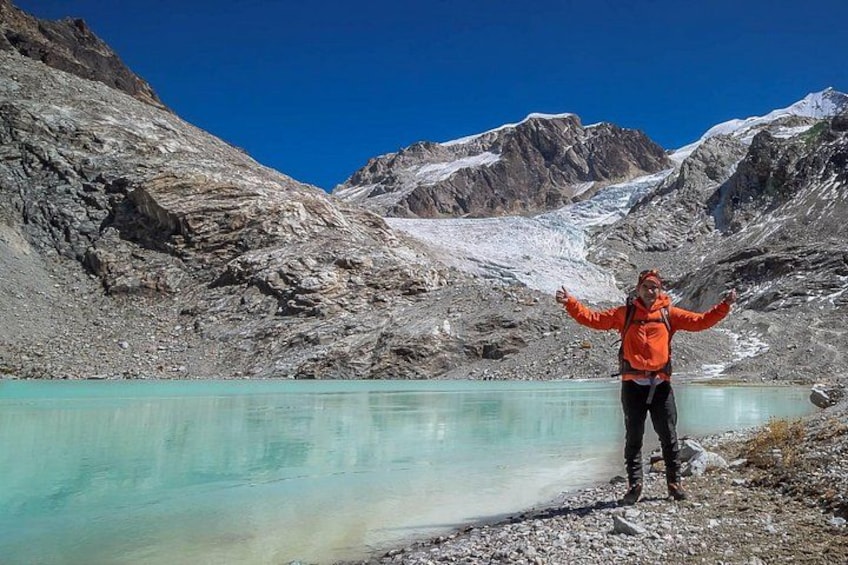 Une personne se tient près d’un lac turquoise, avec des montagnes en arrière-plan. 4