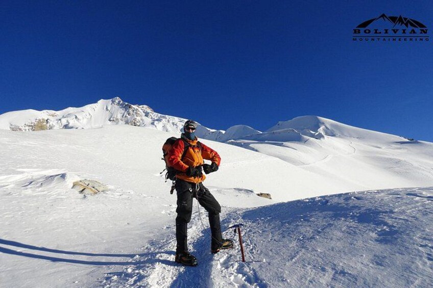 Une personne vêtue d’une tenue d’alpinisme se trouve sur une montagne enneigée, sous un ciel dégagé. 5
