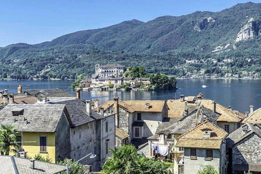 Un pueblo a orillas de un lago con edificios y una estructura imponente similar a un castillo en una isla. 4