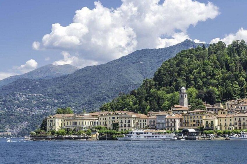 A coastal town with buildings, a tower, and mountains in the background. 2