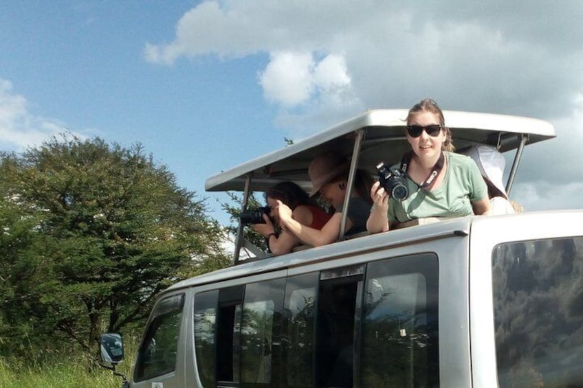 Two people on a vehicle with a roof, one holding a camera. 4