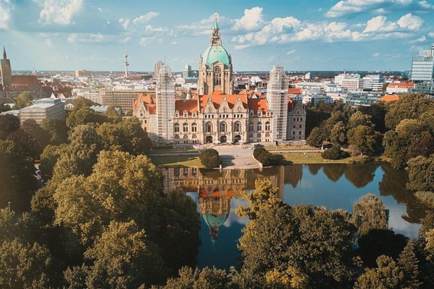 A historic building with a green dome, surrounded by trees and a lake. 5