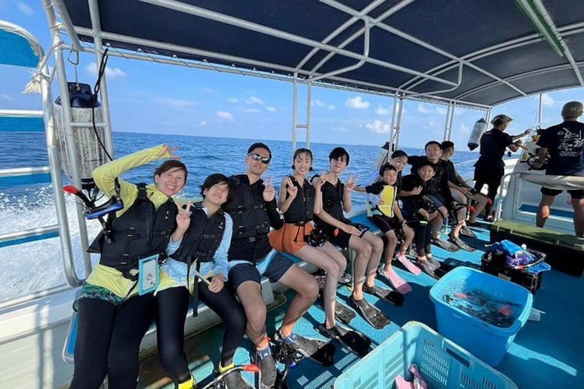A group of people on a boat wearing life jackets, with the ocean in the background. 5