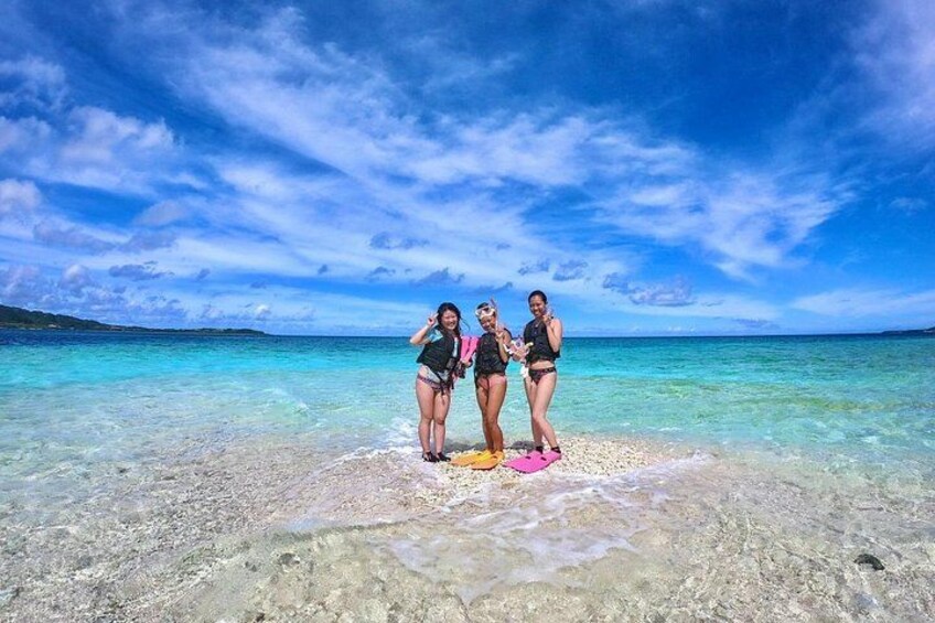 Three people standing on a beach with clear turquoise water and a blue sky. 2