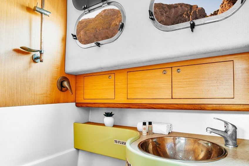 Una cucina con un armadietto in legno, un lavandino e una finestra con vista sulle rocce. 4