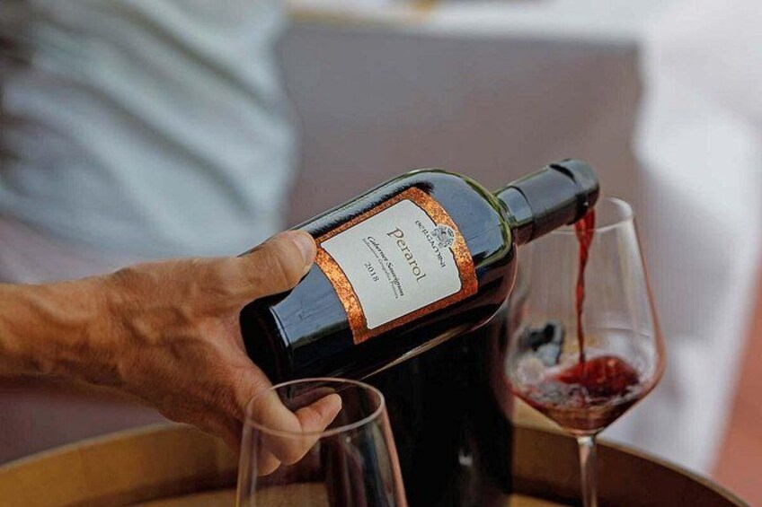 A person pouring wine from a bottle into a glass. 2