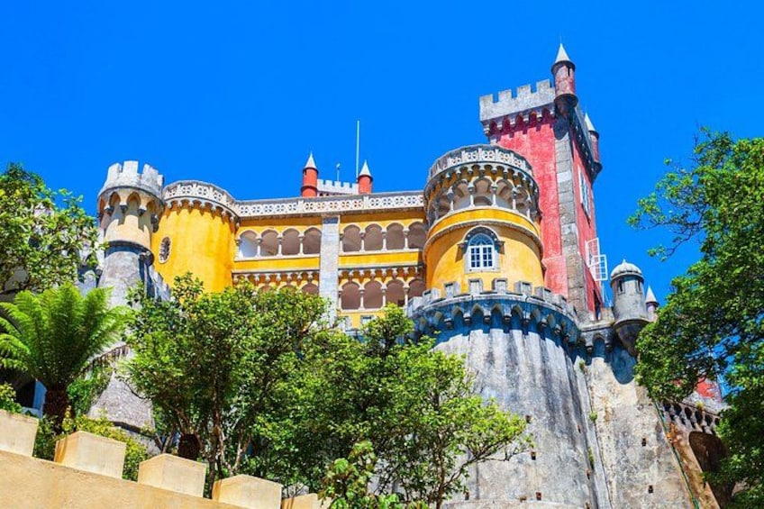 Un castillo con muros amarillos y rojos, torres y un cielo azul despejado. 3