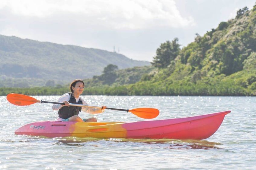 A person kayaking on a calm river with a forested landscape in the background. 3