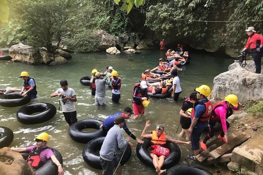 People rafting in a river surrounded by rocks and greenery. 1