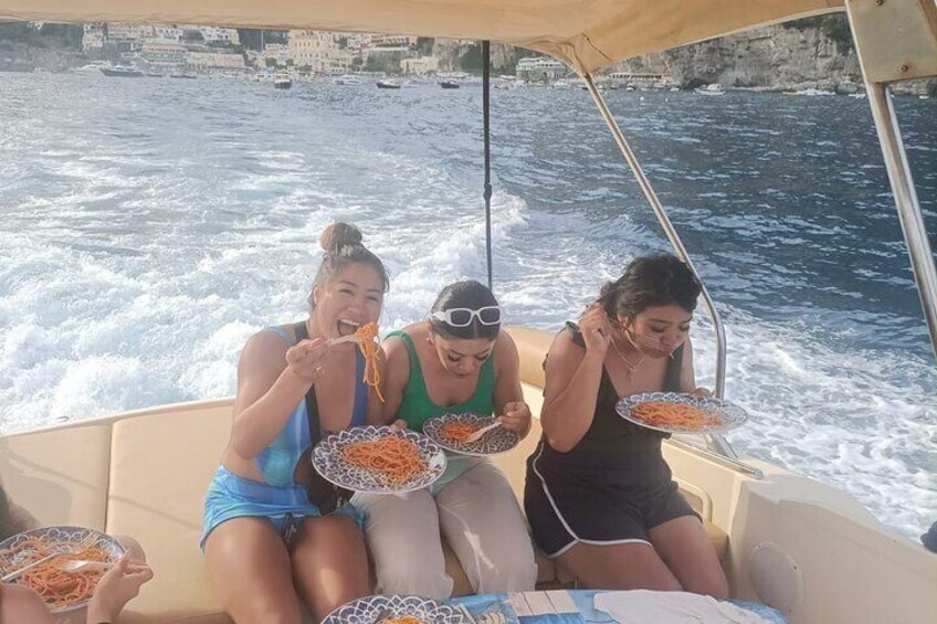 Three people on a boat eating spaghetti. 4