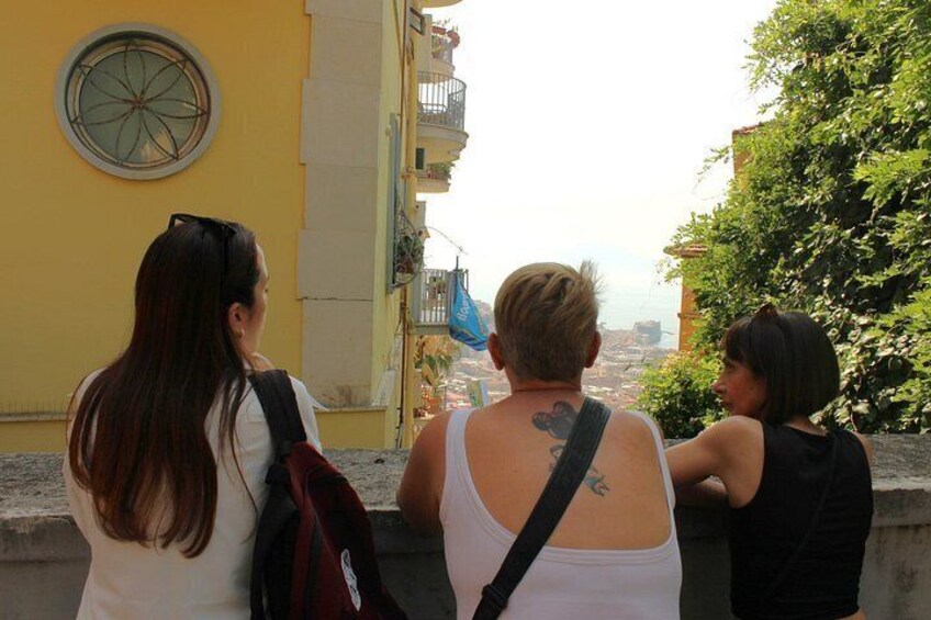 Three people standing on a balcony overlooking a cityscape. 5