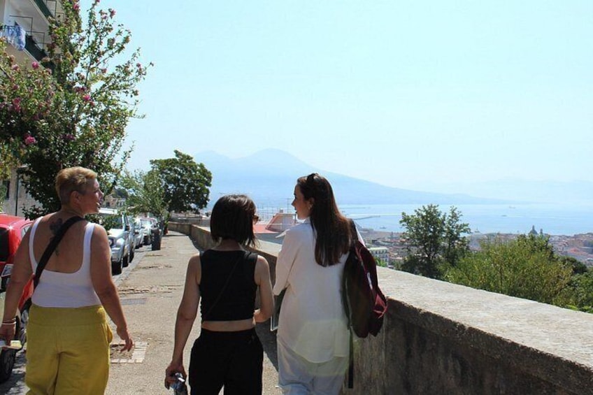 A group of people walking on a coastal path with a view of the sea and mountains in the distance. 4
