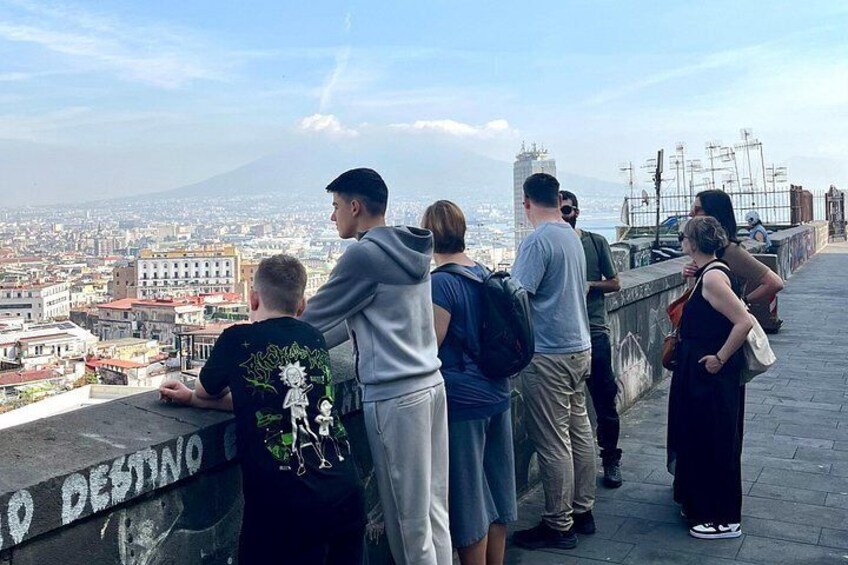 A group of people standing on a ledge overlooking a cityscape with a mountain in the distance. 3