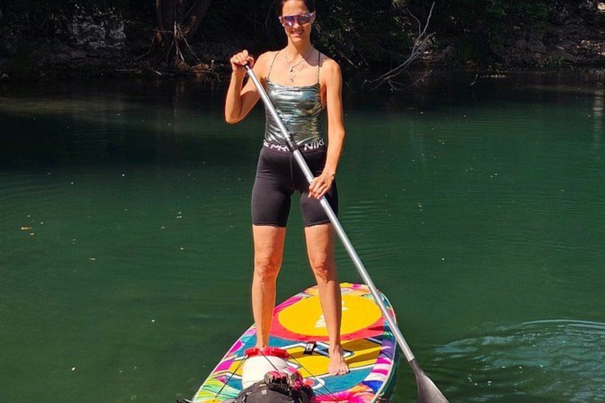 A person standing on a colorful paddleboard in a body of water. 3