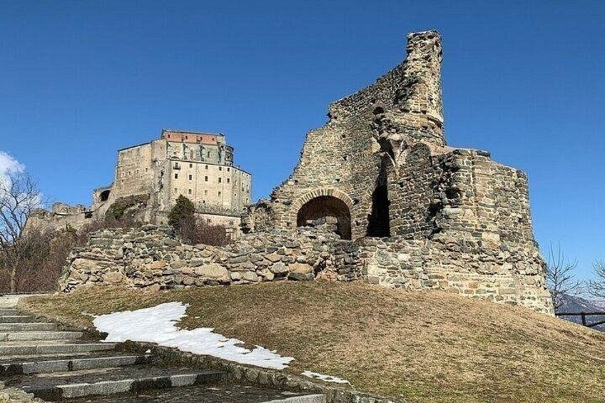 A historical stone structure with a partially intact building and a large arched doorway. 5
