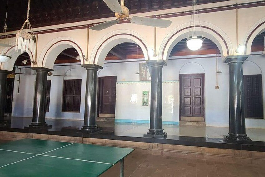 A tennis court with a net, surrounded by columns and arches. 4