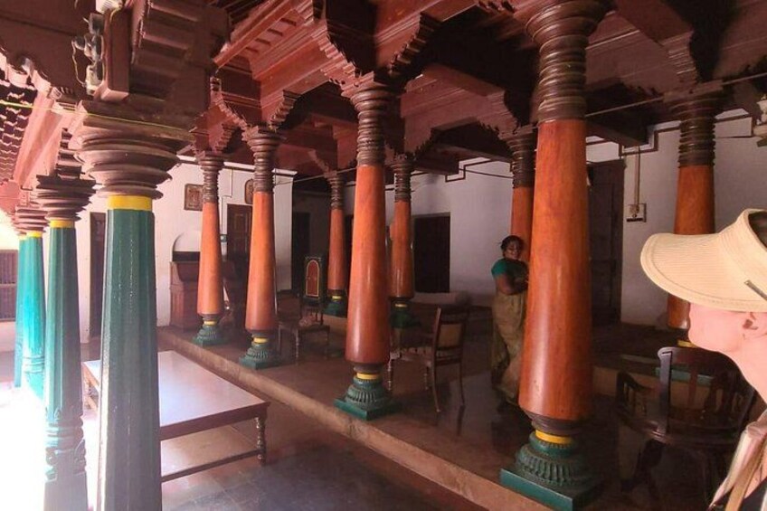 A traditional building with ornate wooden pillars and a person in the background. 3