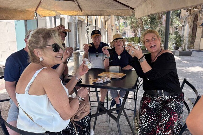 Personas sentadas en una mesa al aire libre, comiendo y bebiendo. 2