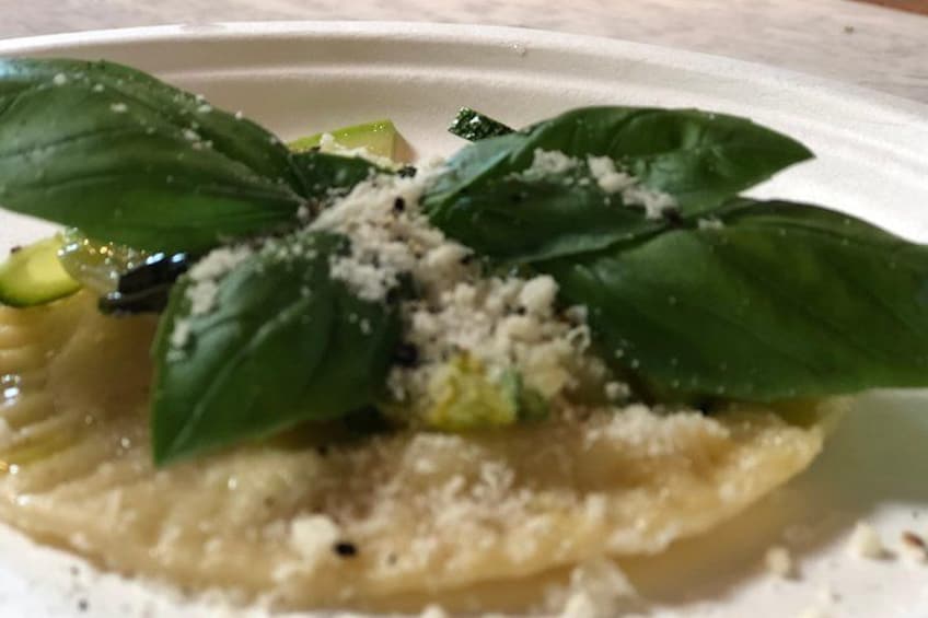 Un plato de ravioles con hojas de albahaca y queso rallado. 2