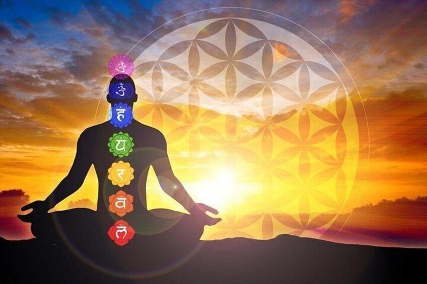 A silhouette of a person meditating with chakras on their body against a sunset. 2