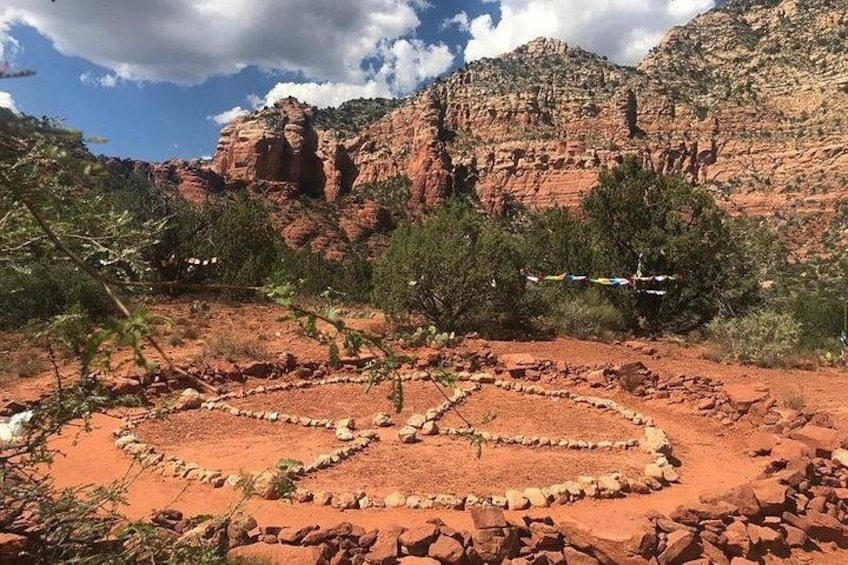 A desert landscape with red rock formations, a heart-shaped stone arrangement, and sparse vegetation. 3