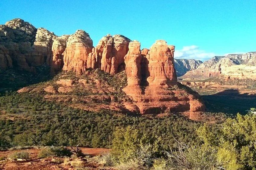 A rugged mountain landscape with prominent red rock formations and a dense forest at the base. 2