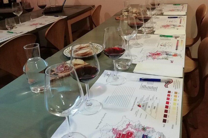 A table set for a wine tasting event with wine glasses, tasting sheets, and food. 5