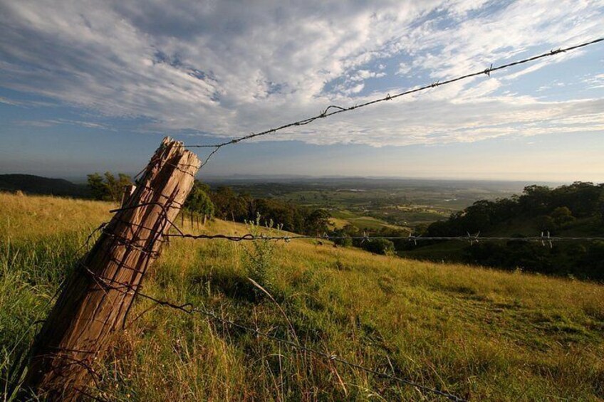 A barbed wire fence, grassy terrain, and a distant landscape. 3