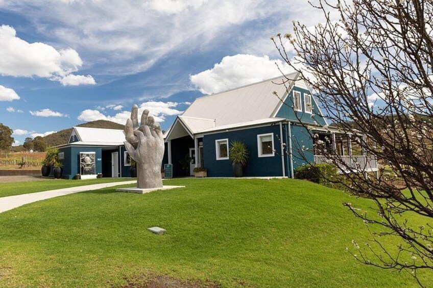 A house with a large hand sculpture in front, a well-maintained lawn, and a clear blue sky. 4