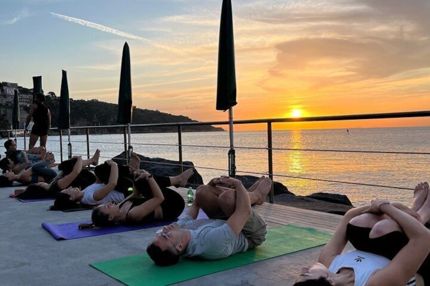 People practicing yoga on mats by the seaside during sunset. 3