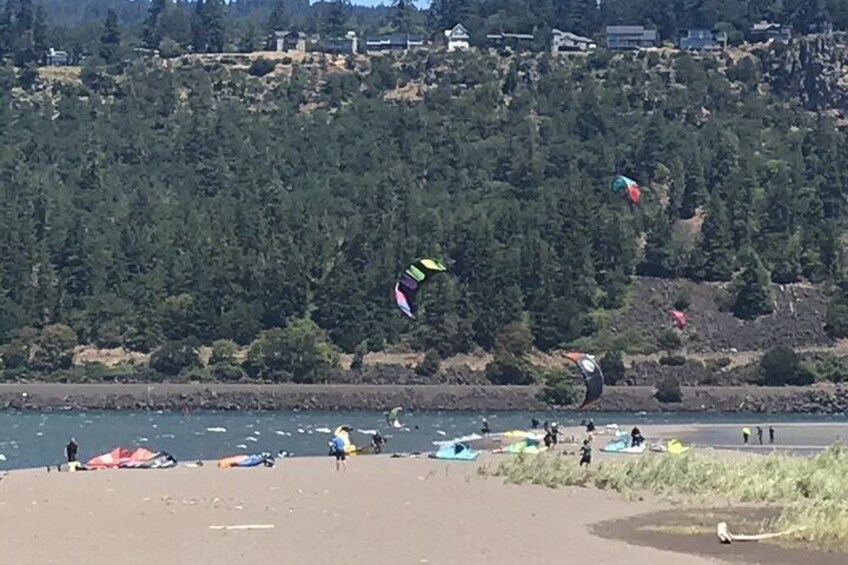 Een strand met mensen die vliegeren en een rivier op de achtergrond. 2