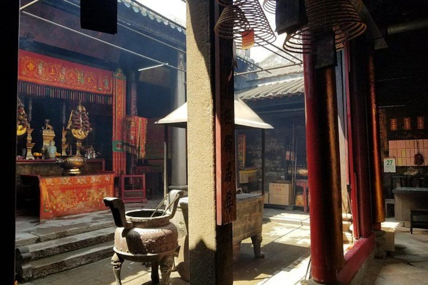 L’intérieur d’un temple à l’architecture traditionnelle, avec notamment un autel en pierre, des brûleurs d’encens et une cloche. 2