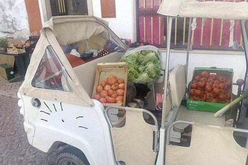 A small vehicle with a triangular front, carrying boxes of tomatoes and lettuce. 2