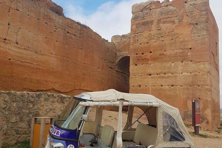 A vehicle with a canopy parked near a large rock formation. 1