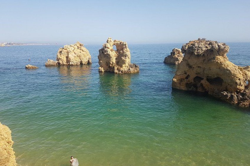 Mar azul y despejado, formaciones rocosas y una costa lejana. 3