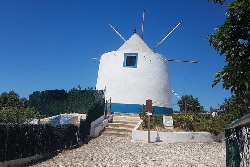 Un molino blanco con detalles azules, un camino empedrado que lo lleva a él, y un cielo azul despejado. 2