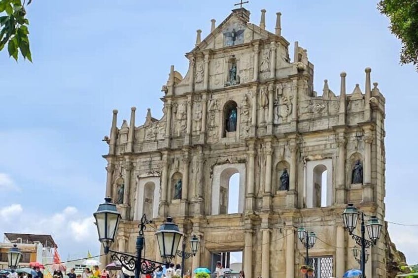 A historic stone cathedral with multiple arches and statues, surrounded by street lamps and a clear sky. 1