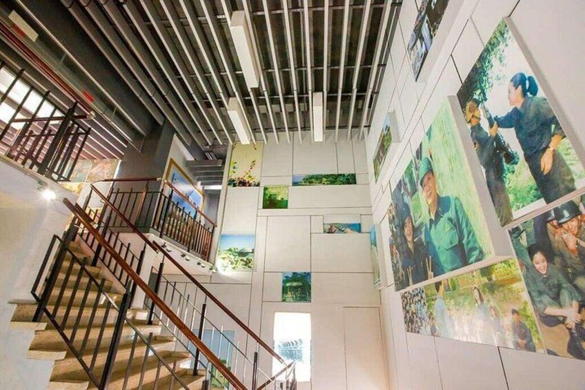 A multi-level interior space with a staircase, wooden railings, and walls adorned with photographs. 5
