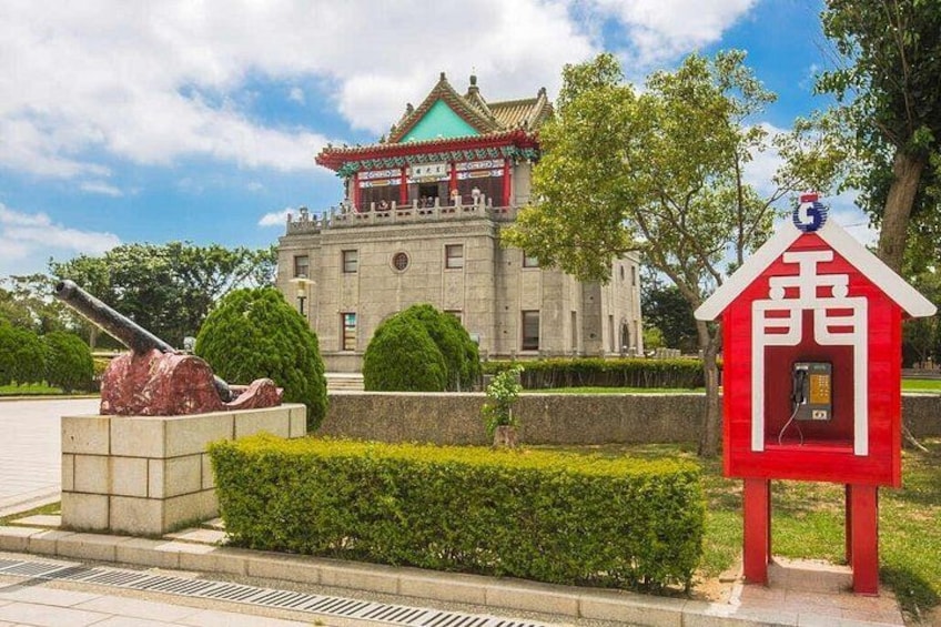 A traditional building with a red roof, a red telephone booth, and a large cannon. 1
