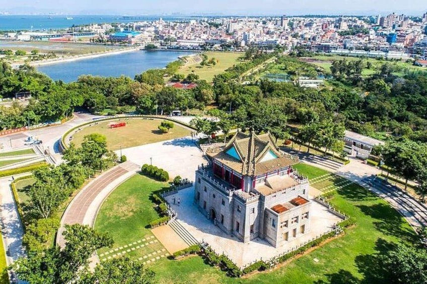 A large, historic building with a prominent tower, surrounded by green spaces and a waterfront. 2