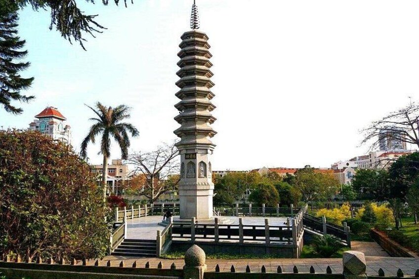 A pagoda-style tower with a spiral staircase, surrounded by greenery and urban buildings in the background. 5