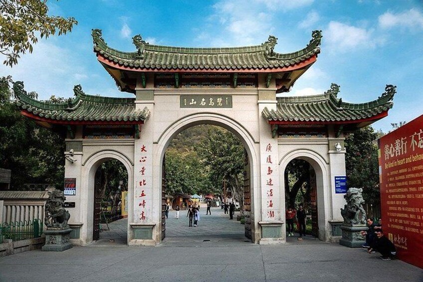 A traditional Chinese gate with intricate roof designs and stone pillars, leading into a park. 4