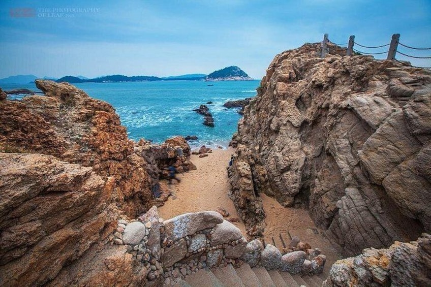 A rocky coastal landscape with a clear view of the sea and distant islands. 5