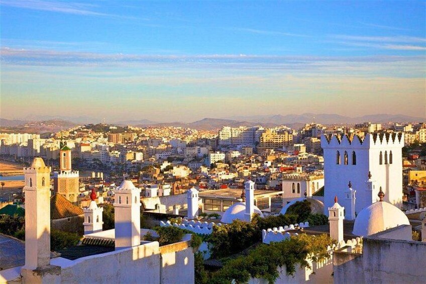 A cityscape with white buildings, a prominent white tower, and a clear blue sky. 1