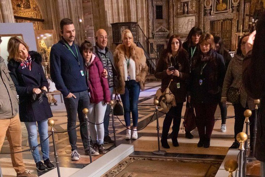 Un groupe de personnes se tient dans un musée ou un bâtiment historique, caractérisé par une architecture riche et un grand escalier. 1