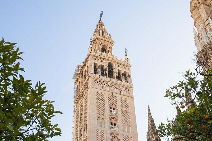 A tall, ornate tower with intricate architectural details, surrounded by trees with green leaves. 4