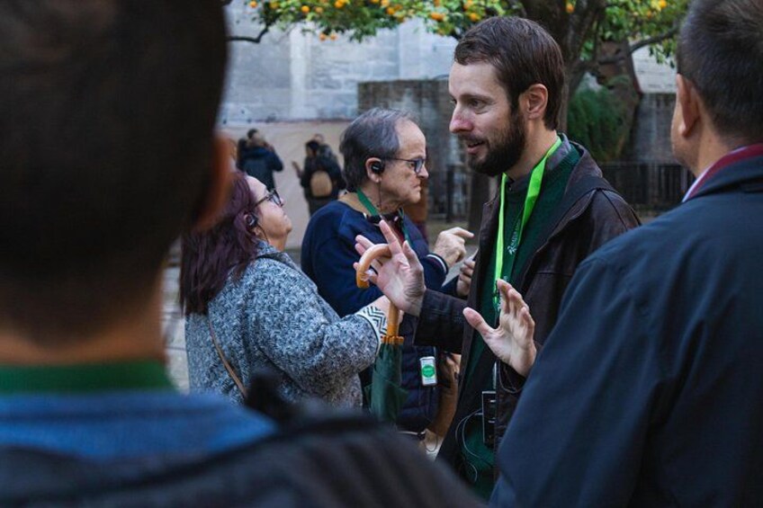 Un groupe de personnes est engagé dans une conversation à l’extérieur, avec un bâtiment et des arbres en arrière-plan. 2