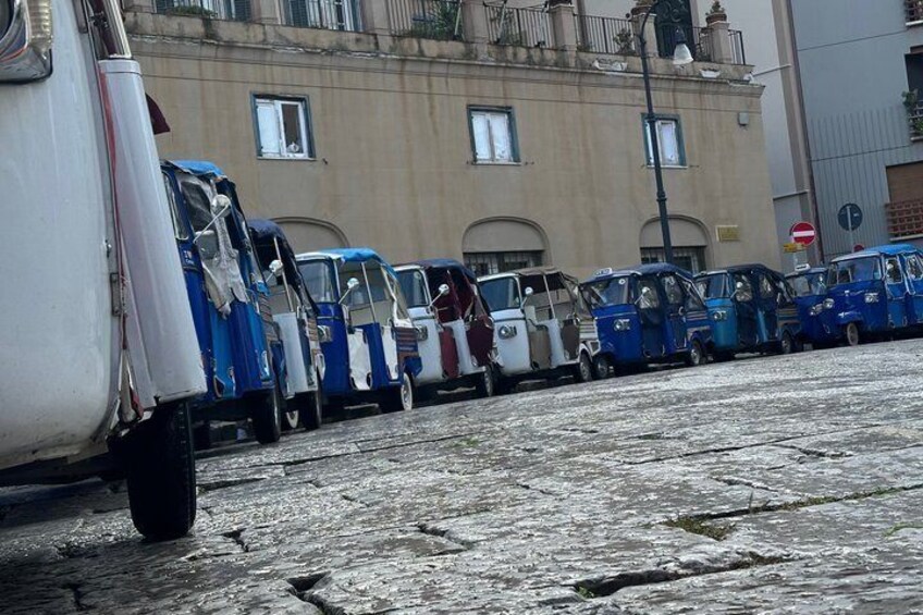 A row of blue and white vehicles parked on a cobblestone street. 5